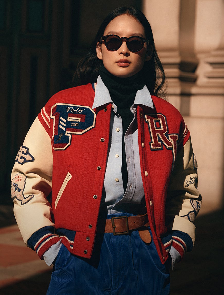 Woman wearing red varsity jacket and blue pants 