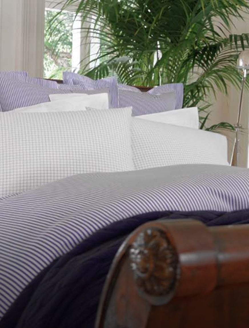 Wood bed appointed with blue-and-white striped linens.