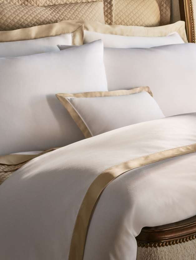 White-and-gold pillows and blankets on a bed.