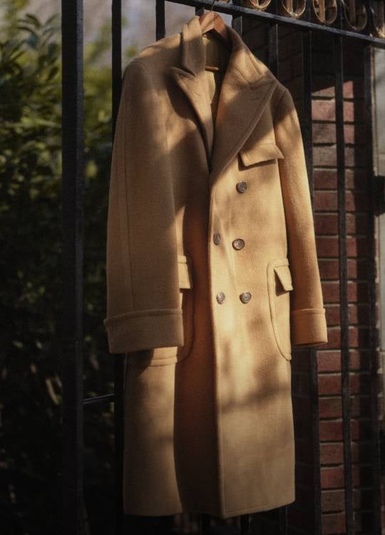 Camel-hair Polo coat on hanger on fence.