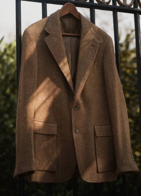 Tweed jacket hanging on wood hanger.